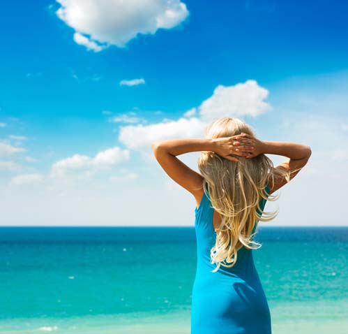 woman at beach with hands on back of head