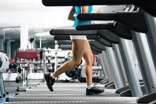 young woman in shorts running on treadmill