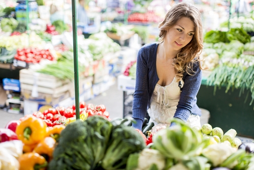 young woman at market looking at vegetables