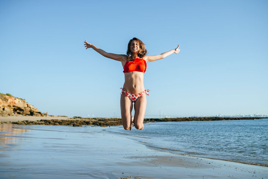 Young woman on beach in bikini jumping