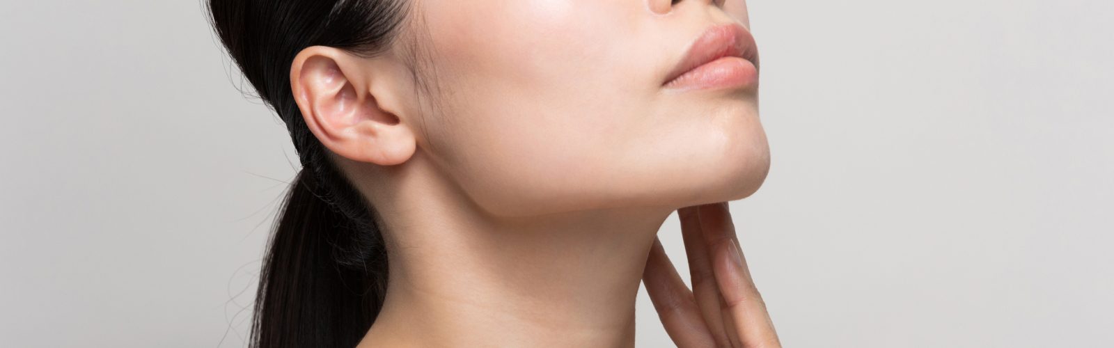 Closeup of woman resting her fingers on her neck area.