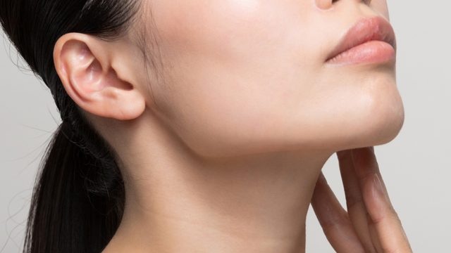 Closeup of woman resting her fingers on her neck area.