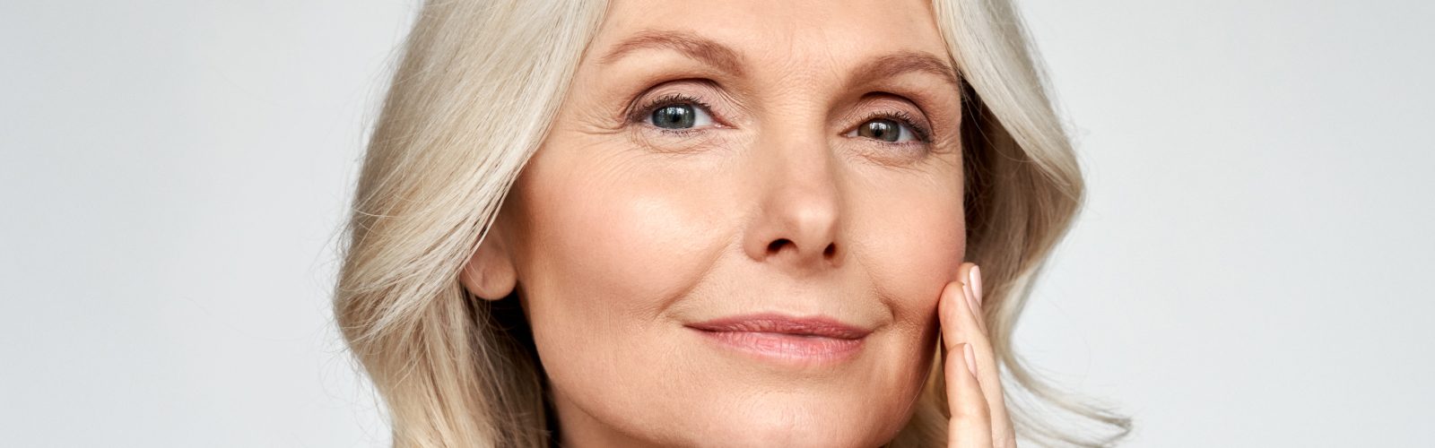 Closeup of blonde woman with her left hand on her cheek.