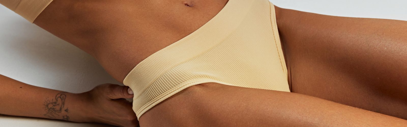 Closeup of woman's lower body wearing light yellow bikini bottoms.