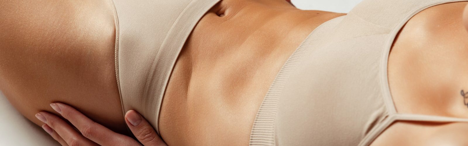 Closeup of woman's stomach area wearing light colored bra and underwear.