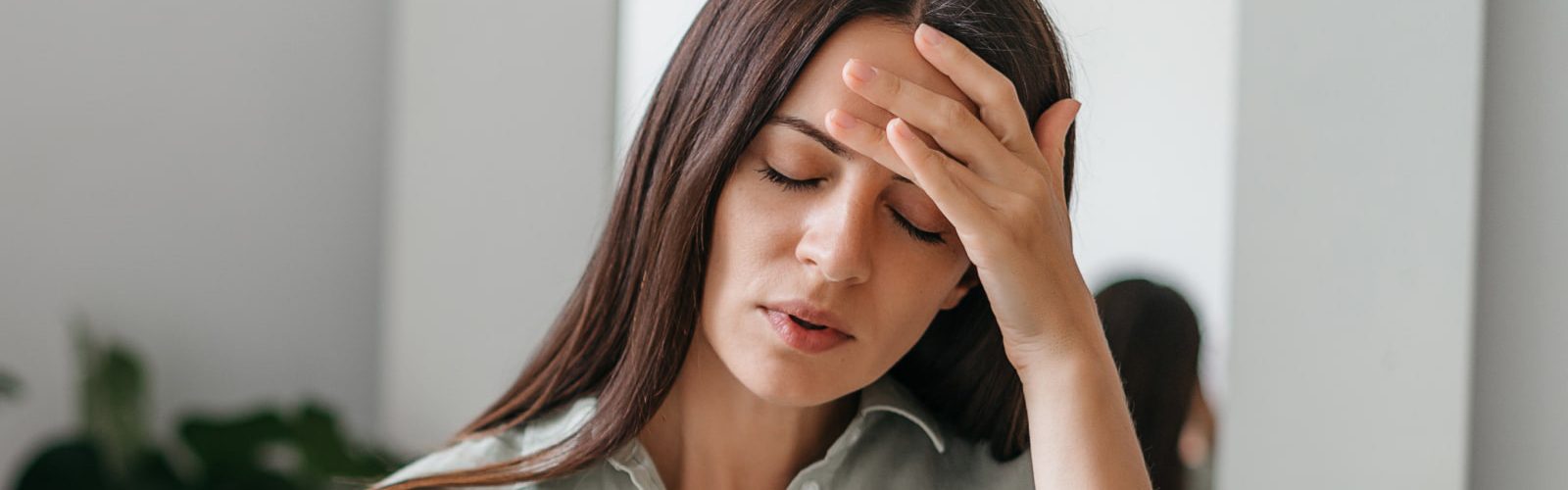 Woman with hand on her head and eyes closed looking stressed.