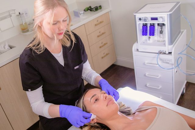 Female in a clinic laying down receiving DiamondGlow treatment by an aesthetic specialist.