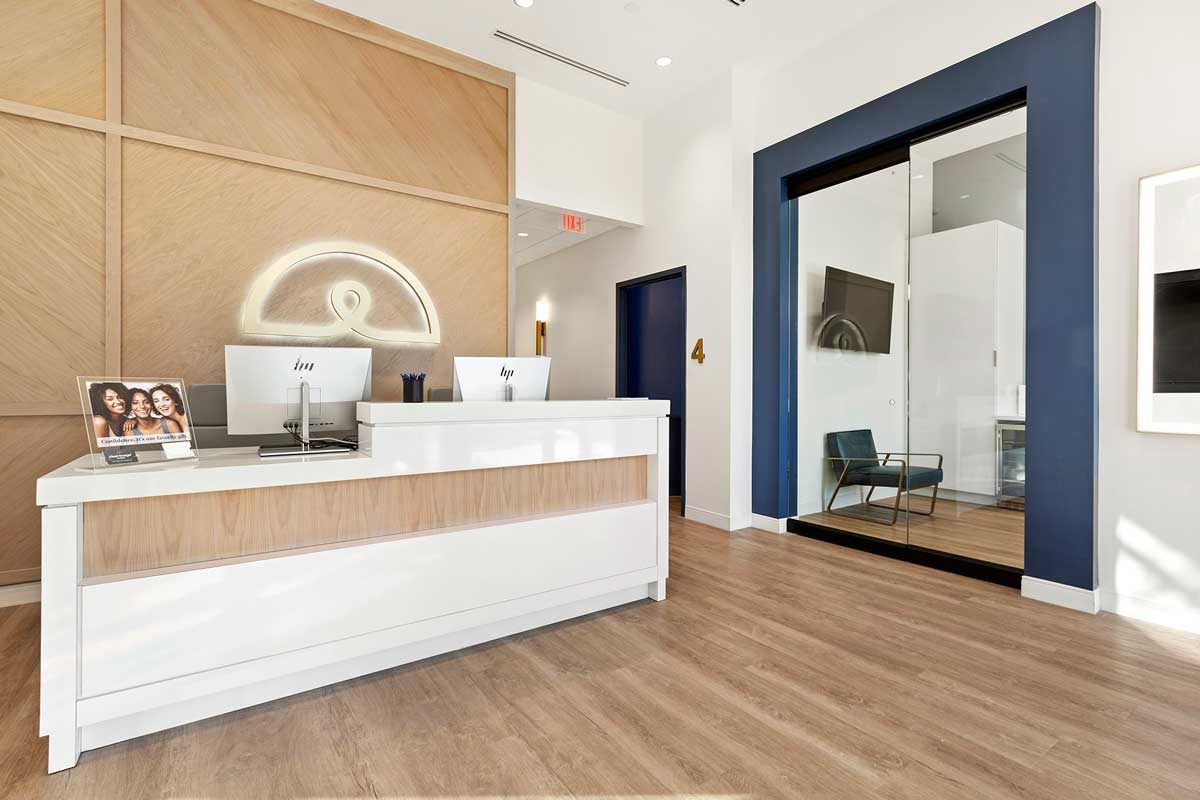 Lobby area of an Ideal Image clinic with a reception desk with two computer monitors.