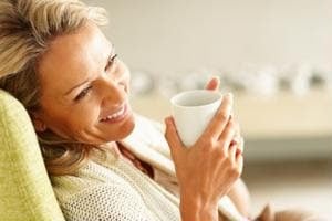 Woman smiling while holding a white coffee cup