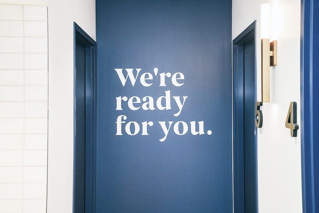 Ideal Image clinic hallway with treatment rooms and sign that states "We're ready for you"