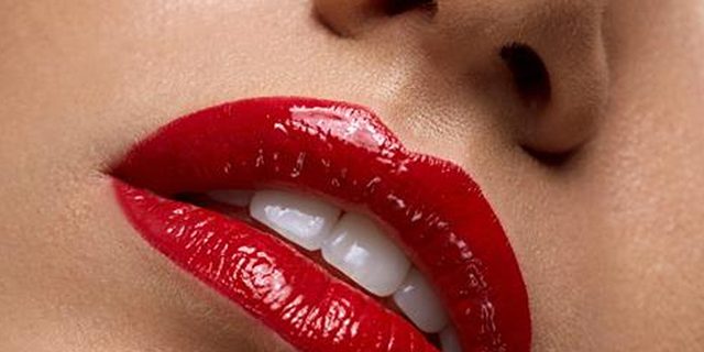 A closeup of a woman's lips wearing red lipstick.