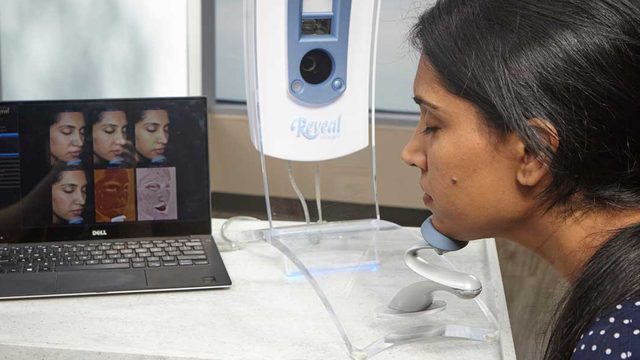 Woman resting chin on Reveal machine.