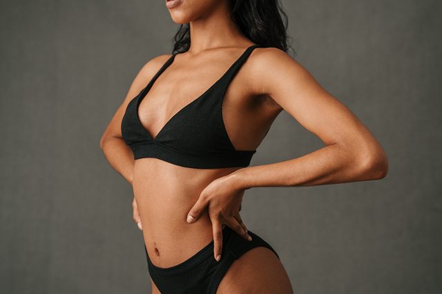 Female with dark hair wearing black bra and lingerie.