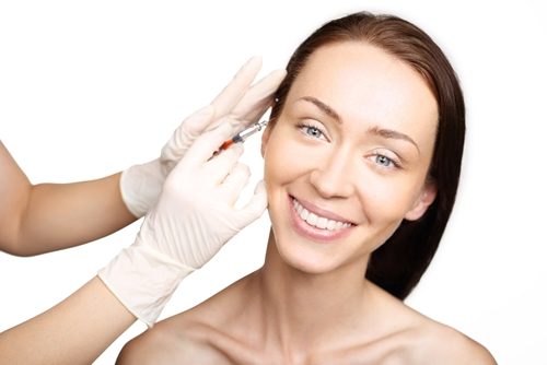 Woman smiling while receiving a face injection.