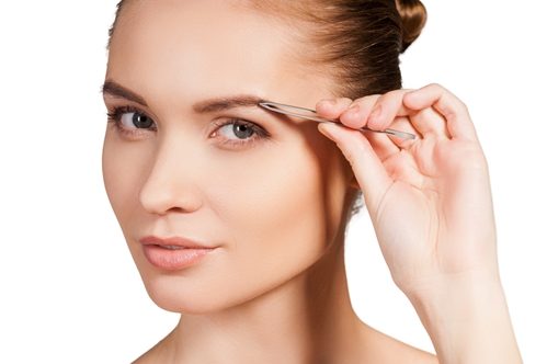 Adult female styling her eyebrows.