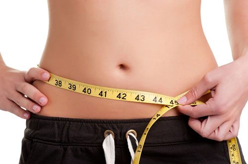 Closeup of a person's stomach region with a measuring tape