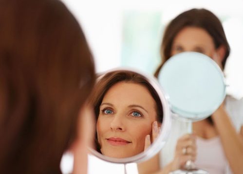 Adult woman looking into a mirror.