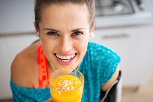 Adult woman smiling while holding yellow smoothie