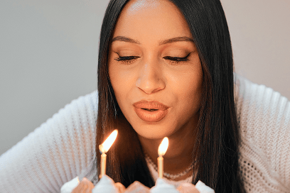 woman blowing out candles on a birthday cake