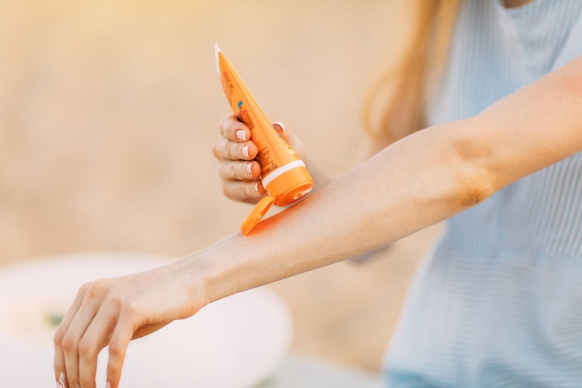 person applying sunscreen to arm