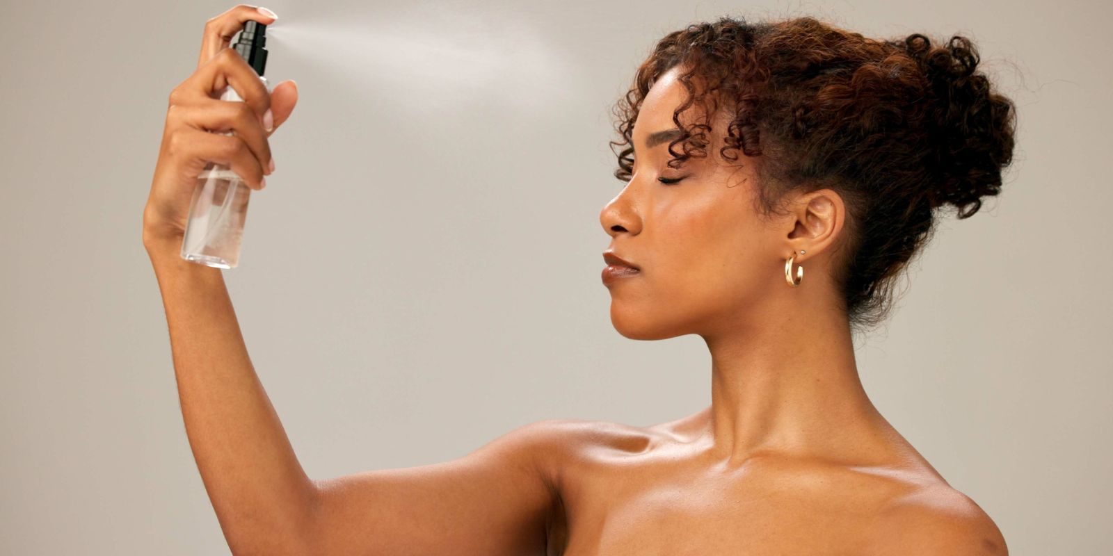 woman applying aerosol skincare to face area