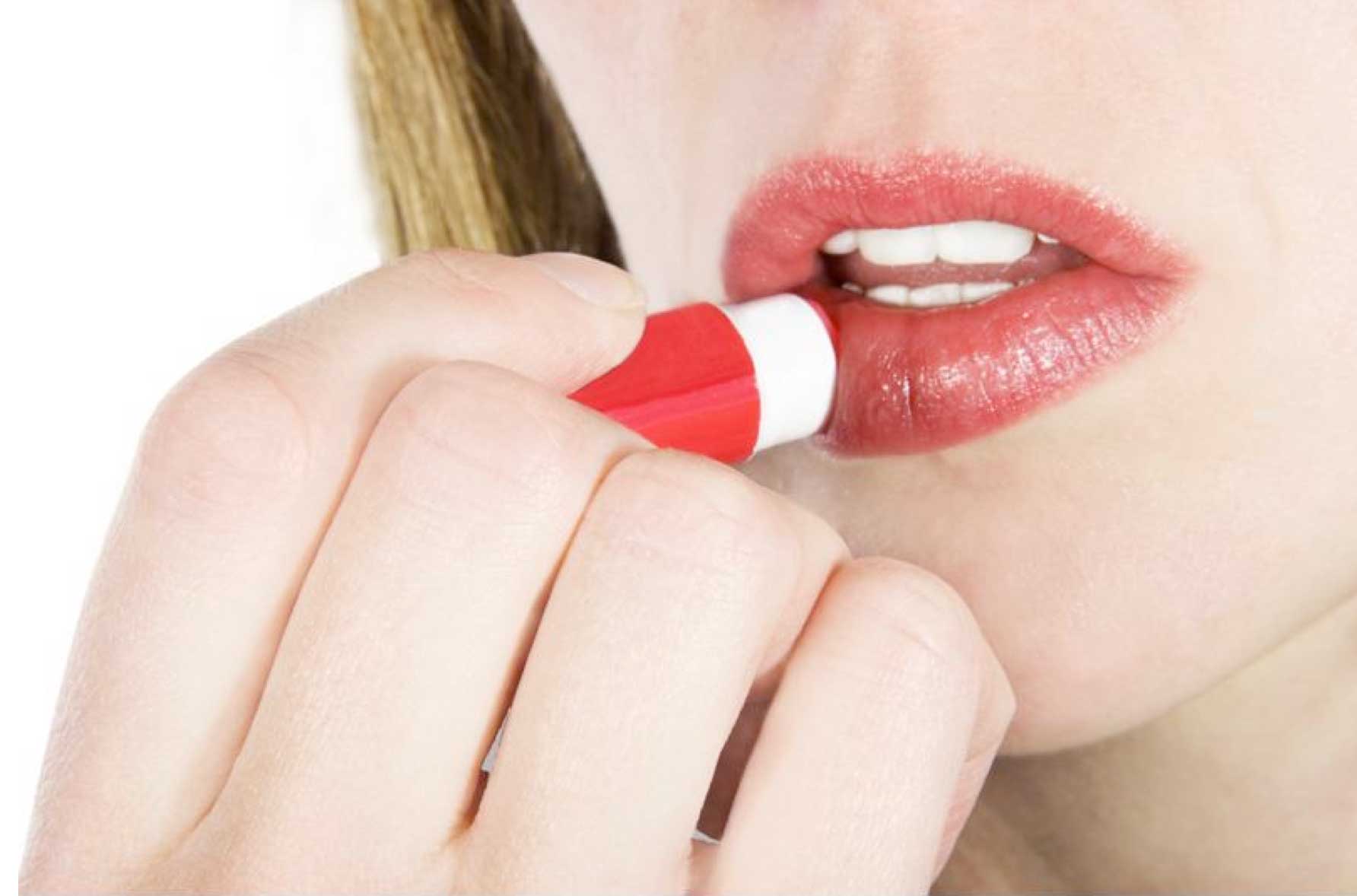 woman putting on lipstick