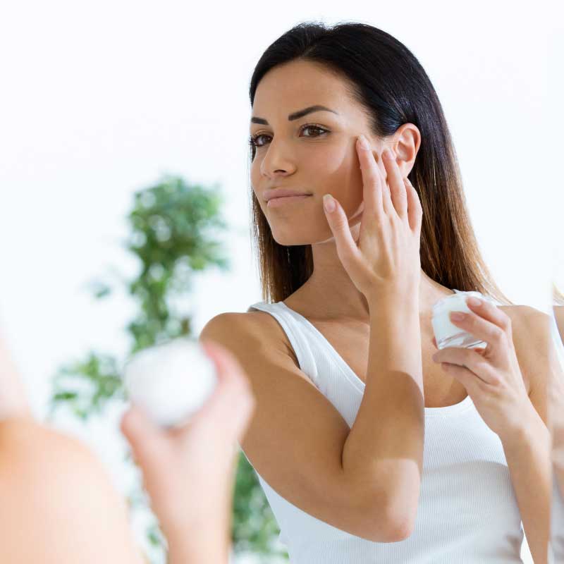woman applying cream to face