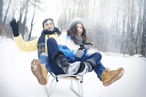 young couple on sled in winter snow