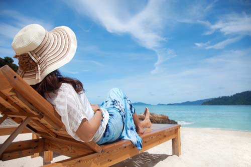 woman sitting on chair on beach with hat