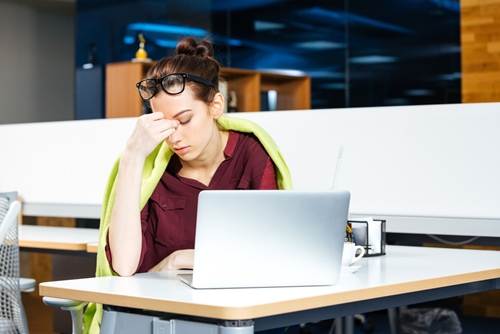 girl with laptop and hand on face looking tired