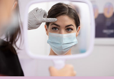 young woman looking in mirror receiving Botox consultation
