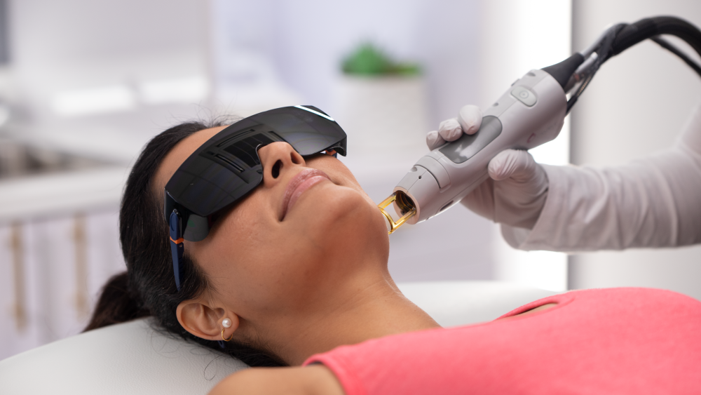 Young woman wearing eye protection and receiving laser hair removal treatment on face